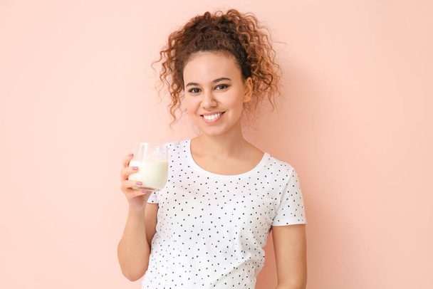 Young African-American woman with milk on color background - Photo, Image