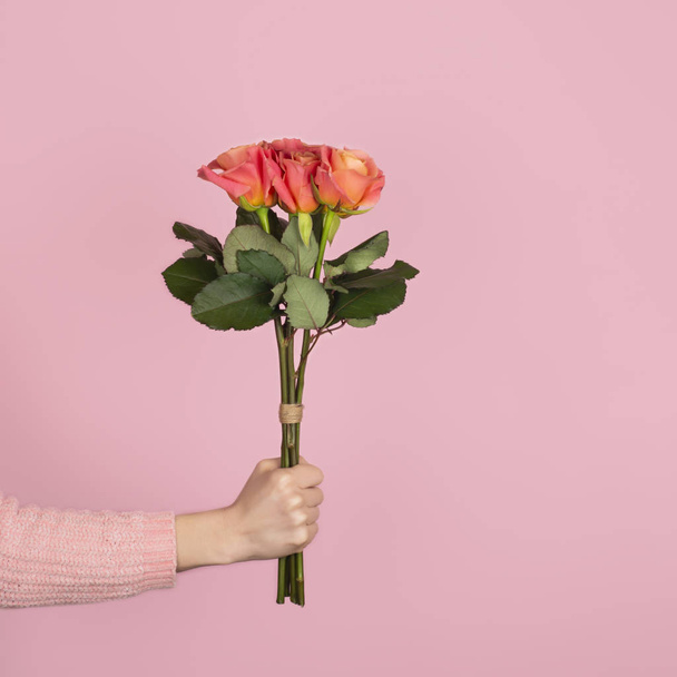 trendiger Strauß zartrosa Rosen in weiblicher Hand auf rosa Hintergrund. Banner zum Valentinstag. Kopierraum - Foto, Bild
