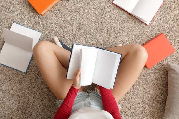 Giovane donna che legge libro a casa, vista dall'alto
 - Foto, immagini