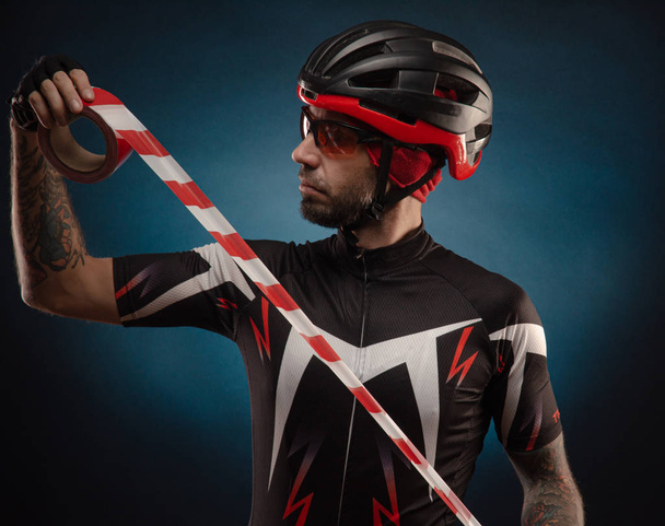 guy-fietser in een fietshelm met een barrière tape - Foto, afbeelding