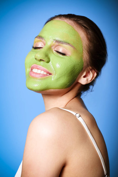 Mulher alegre aplicando máscara verde
 - Foto, Imagem