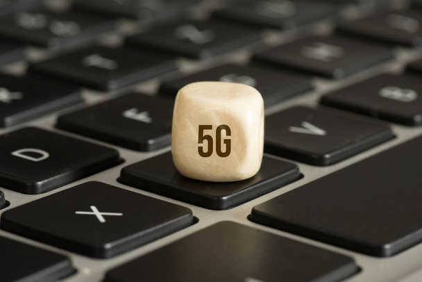 laptop keyboard and wooden dice with 5g sign - 写真・画像