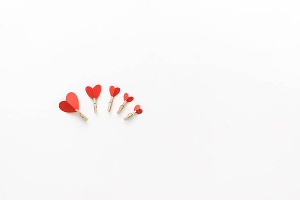Valentine's Day. Beautiful red paper hearts with clothespins on a white surface. Top view. - Zdjęcie, obraz