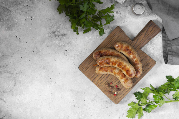 Grilled sausages on a wooden Board on a light gray kitchen table. View top - Фото, зображення