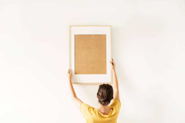 Young pretty woman hold blank photo frame with empty mockup copy space. Minimal art concept. - 写真・画像