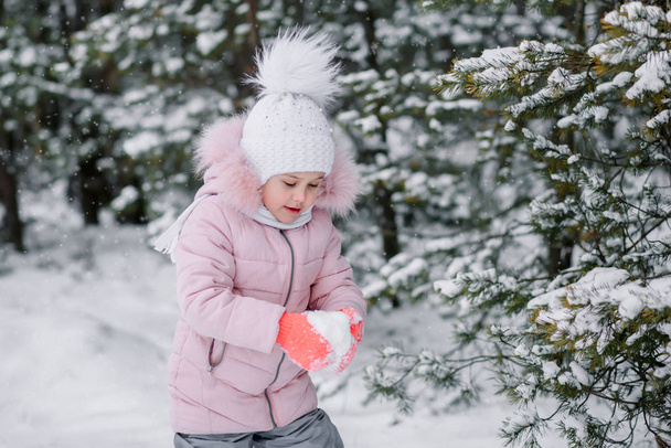 niña juega bolas de nieve al aire libre en invierno
 - Foto, imagen