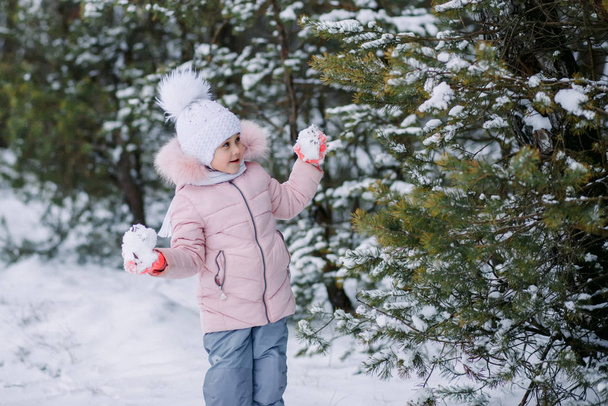 niña juega bolas de nieve al aire libre en invierno
 - Foto, imagen