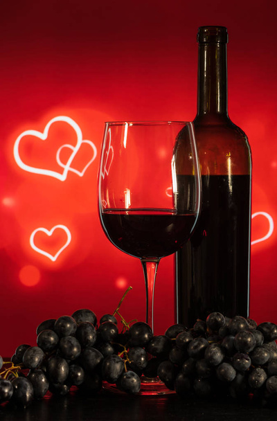 glass with wine and grapes on a red background with hearts - Foto, Bild