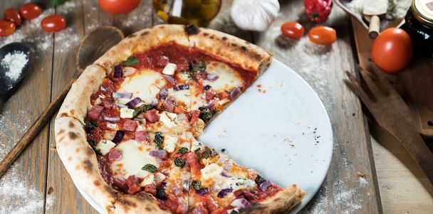 Verse gebakken pizza op houten tafel met ingrediënten - Foto, afbeelding