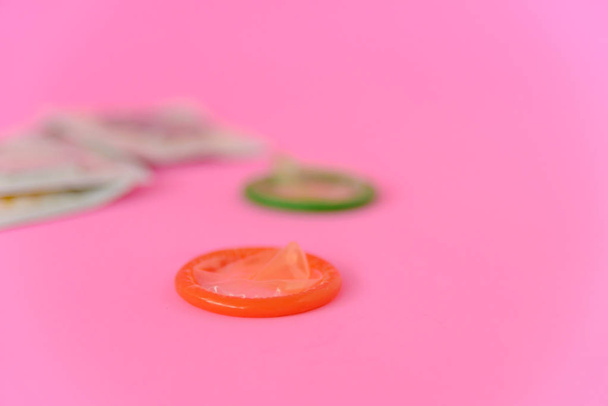 Dva otevřené kondomy s kondomem balení na růžovém papíře pozadí s kopírovacím prostorem pro text. Reprodukční zdraví, antikoncepce a koncepce bezpečného sexu - Fotografie, Obrázek