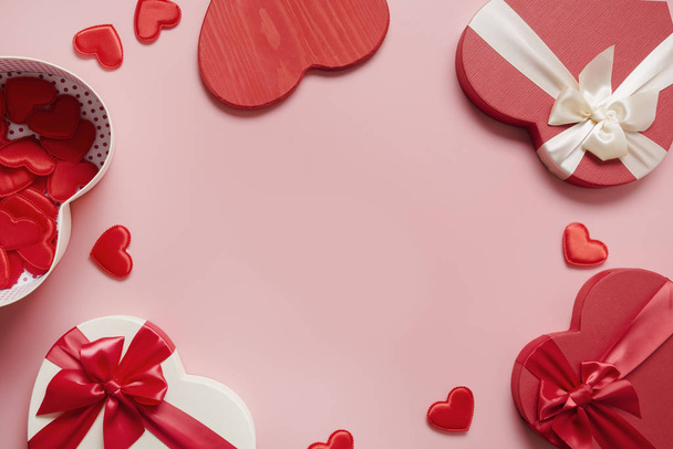 バレンタインデーのグリーティングカード。赤いギフトボックスの心の形とピンクの多くの小さな心のフレーム。上からの眺め。テキストのスペース. - 写真・画像