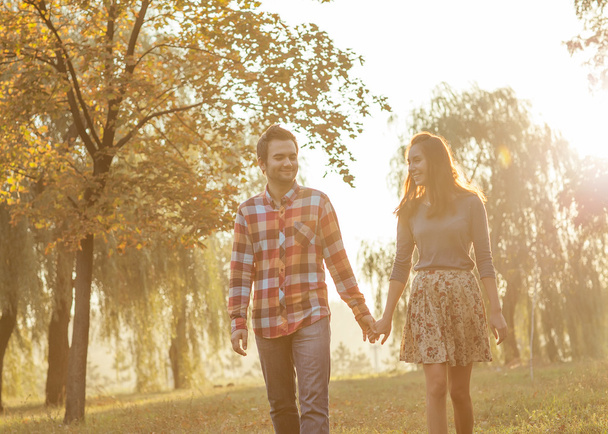 Young couple in love walking in the autumn park near the river. - Фото, зображення