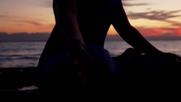 Κοντινό πλάνο γυναίκα σιλουέτα διαλογίζεται κατά της θάλασσας στο πολύχρωμο ηλιοβασίλεμα - Πλάνα, βίντεο