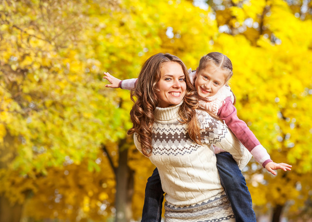 Young mother and her toddler girl have fun in autumn - Фото, изображение