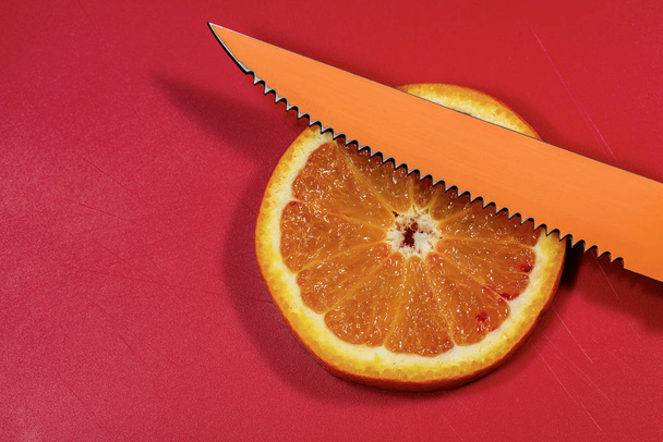 Slice of an orange on a cutting board with knife - Photo, Image