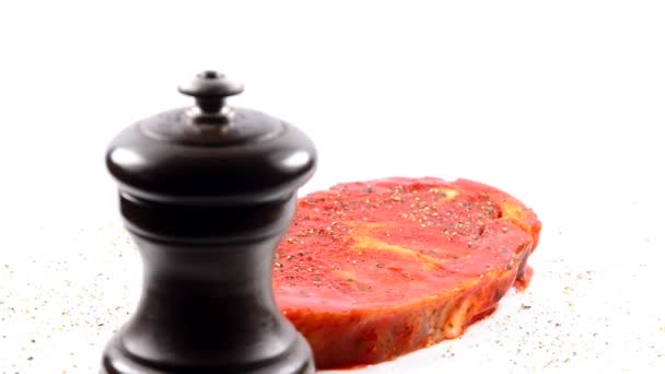 raw and marinated pork neck on a turn table with pepper mill - Footage, Video