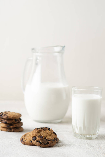 Milk in a jug and chocolate chip cookies on on a white wooden background copy space. - Fotoğraf, Görsel