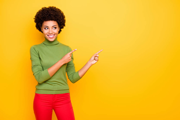 Photo of curly wavy cheerful positive girlfriend with forefingers pointed to the empty space in red trousers showing account to follow isolated bright color background - Foto, imagen
