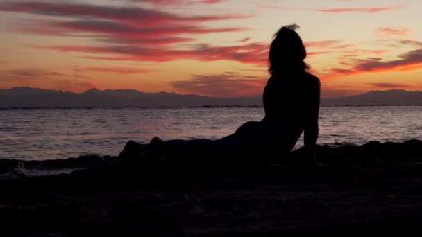 Mulher silhueta medita contra o mar ao pôr do sol colorido
 - Filmagem, Vídeo