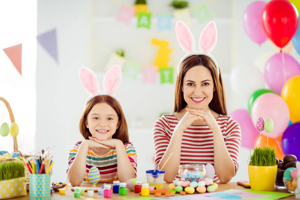 Close-up portrait of nice attractive lovely funny cheerful cheery girls small little daughter wearing bunny ears making handicraft spending day in white light interior room house - 写真・画像
