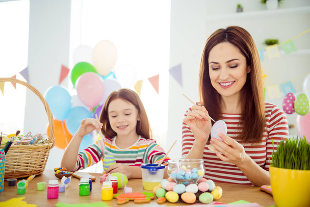 Portrait of nice attractive lovely cheerful cheery girls small little daughter creating festal decor preparing April day spending time in white light interior room house indoors - Photo, image