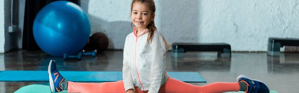 Selective focus of child doing split in gym, panoramic shot - Photo, Image
