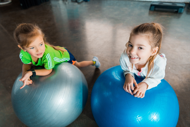 High angle view of children leaning on fitness balls in gym - Fotoğraf, Görsel