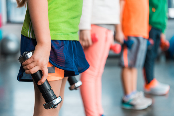 Обрезанный вид на детей, держащих гантели в спорткомплексе
 - Фото, изображение