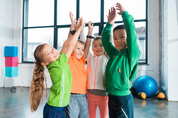 Multiethnic children raising hands up together in gym - Φωτογραφία, εικόνα