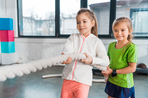 Selective focus of happy children playing tug of war in sports center - Fotoğraf, Görsel