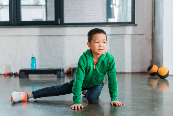 Selective focus of boy stretching in gym - Photo, Image
