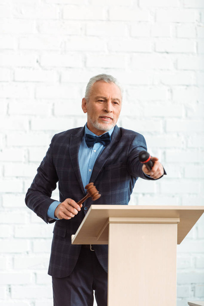 auctioneer holding wooden gavel and microphone and pointing with finger during auction - Photo, Image