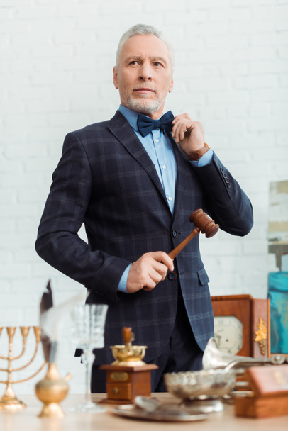 selective focus of handsome auctioneer in suit holding gavel during auction - Photo, Image