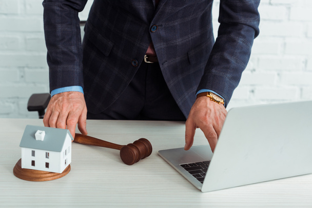cropped view of auctioneer holding gavel and using laptop  - Photo, Image