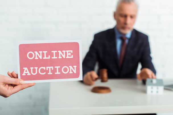 cropped view of woman holding card with online auction lettering and auctioneer holding gavel  - Фото, изображение