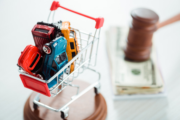 selective focus of shopping trolley with models of cars  - Фото, изображение