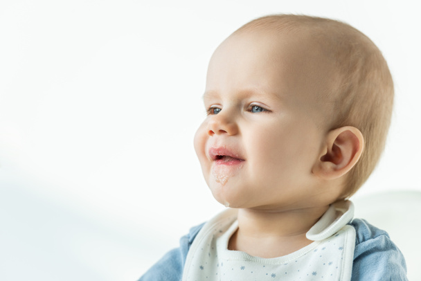 Roztomilý chlapeček se zašpiněnými ústy dívá pryč na bílém pozadí - Fotografie, Obrázek
