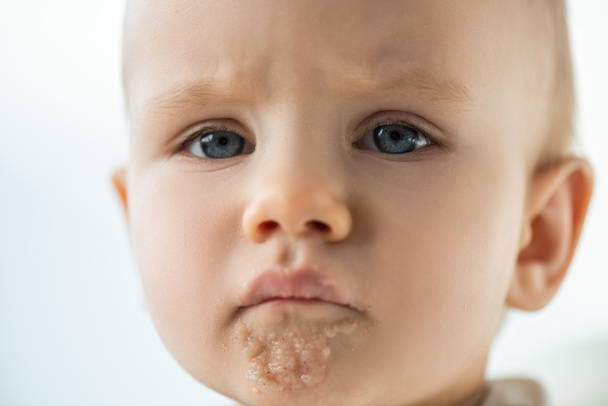Portrait of sad baby boy with puree on soiled mouth isolated on grey - Fotoğraf, Görsel