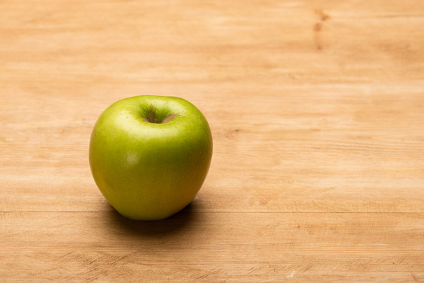 Close up view of green apple on wooden surface - Foto, imagen