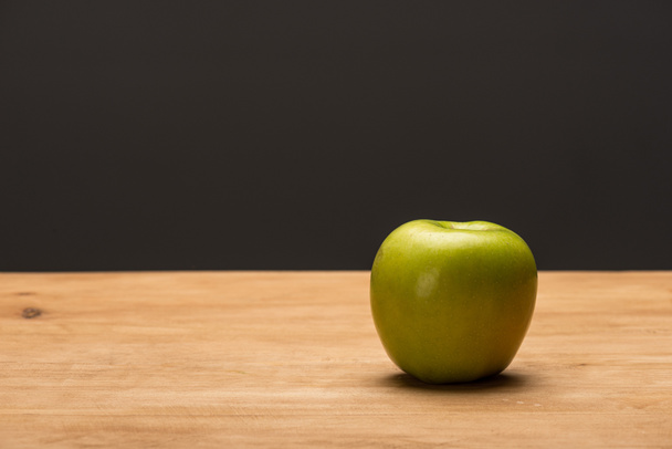 Manzana verde sobre superficie de madera aislada sobre negro
  - Foto, Imagen