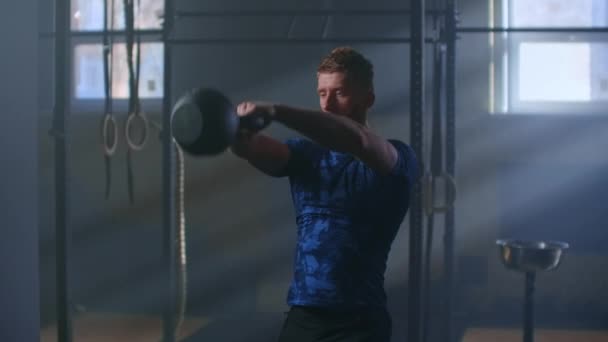 Slow motion: Man doing exercise with kettlebell in gym. fitness athletes men training muscular bodybuilders using kettlebell weights doing intense strength exercise in gym. - Video