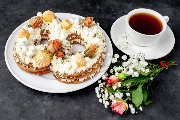 thee en cake in de vorm van 8 versierd met bloemen, roomkaas, marshmallows, Bizet op een stenen achtergrond, heerlijk ontbijt op Internationale Vrouwendag 8 maart - Foto, afbeelding