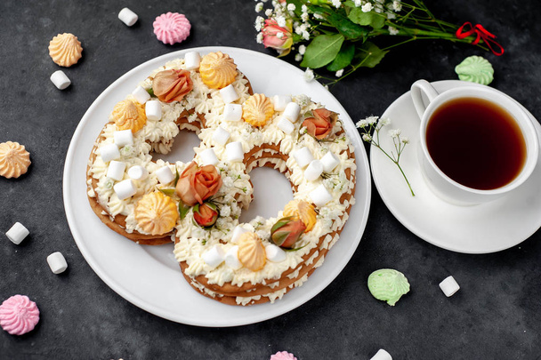 thee en cake in de vorm van 8 versierd met bloemen, roomkaas, marshmallows, Bizet op een stenen achtergrond, heerlijk ontbijt op Internationale Vrouwendag 8 maart - Foto, afbeelding