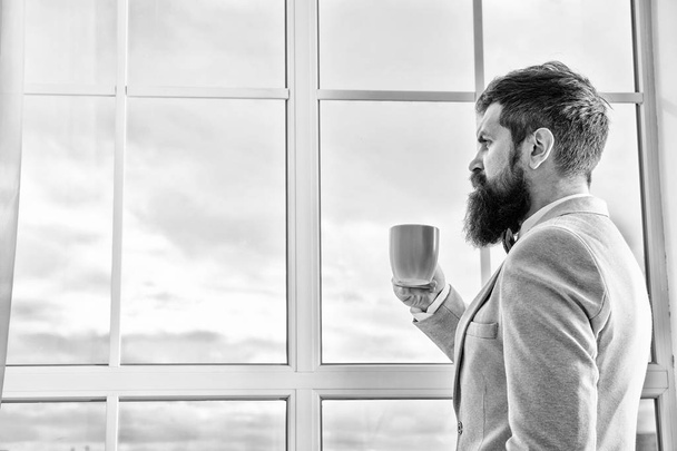His big day. Wedding morning concept. Wedding day. Groom bearded hipster man wear blue tuxedo and bow tie. Man stand at window nervous about wedding. Life choices and expectations. But first coffee - Foto, Bild