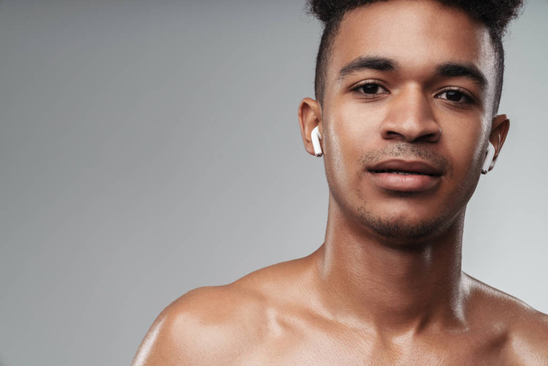 Photo closeup of shirtless african american man using earpods - Photo, Image