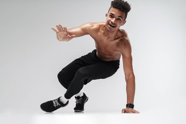 Photo of african american man using earpods and doing exercise - Zdjęcie, obraz