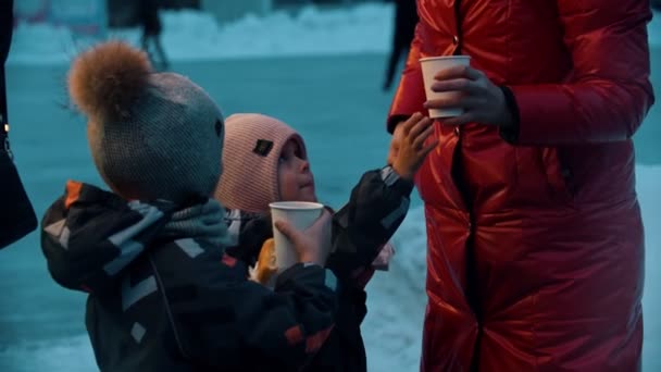 Jovem loira com seus filhos bebendo bebidas quentes e comendo donuts
 - Filmagem, Vídeo
