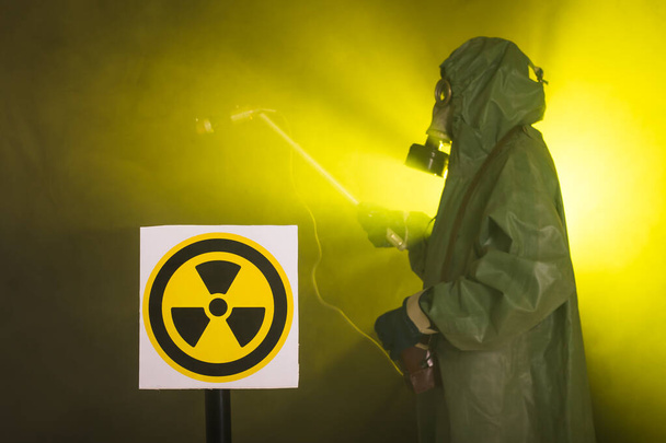 Promieniowanie, zanieczyszczenie i koncepcja zagrożenia - człowiek w odzieży ochronnej i masce gazowej na ciemnym tle - Zdjęcie, obraz
