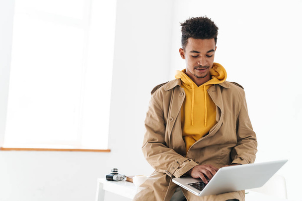 Photo of young african american man typing on laptop while sitting - Photo, image