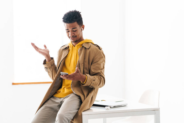 Photo d'un homme afro-américain confus utilisant un téléphone portable et un écouteur
 - Photo, image
